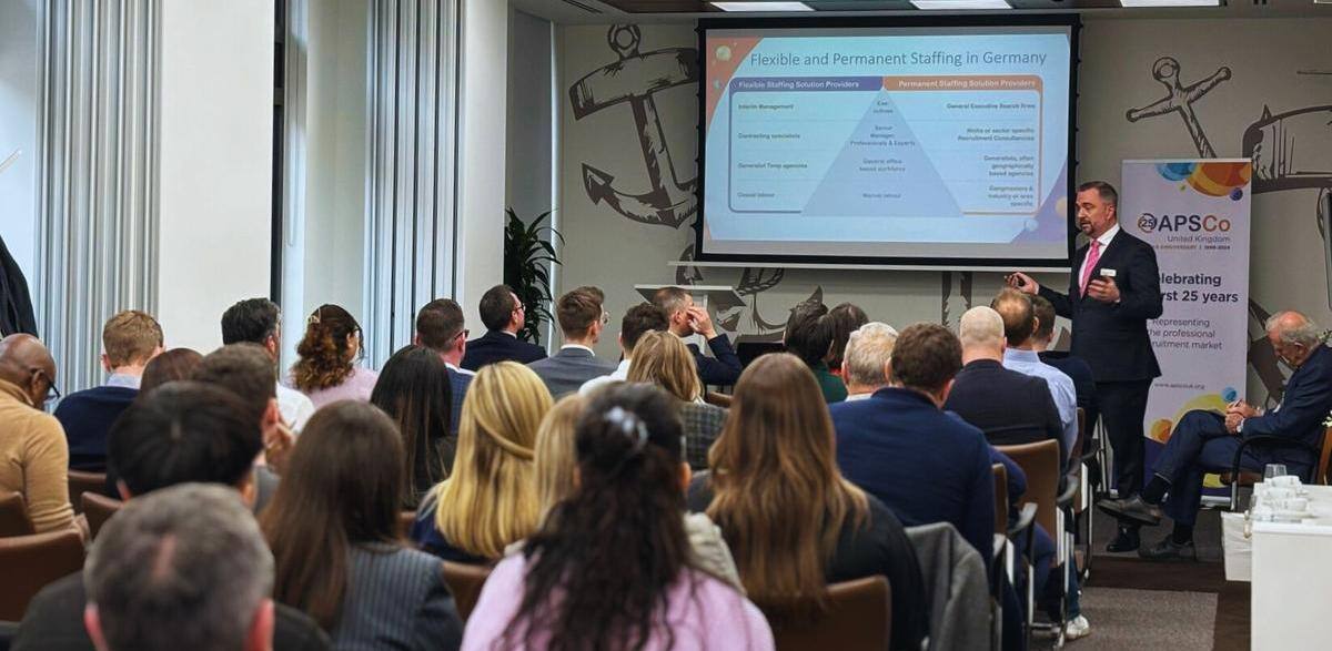 A photo of an international forum hosted in Germany; a room filled with people watching a presentation