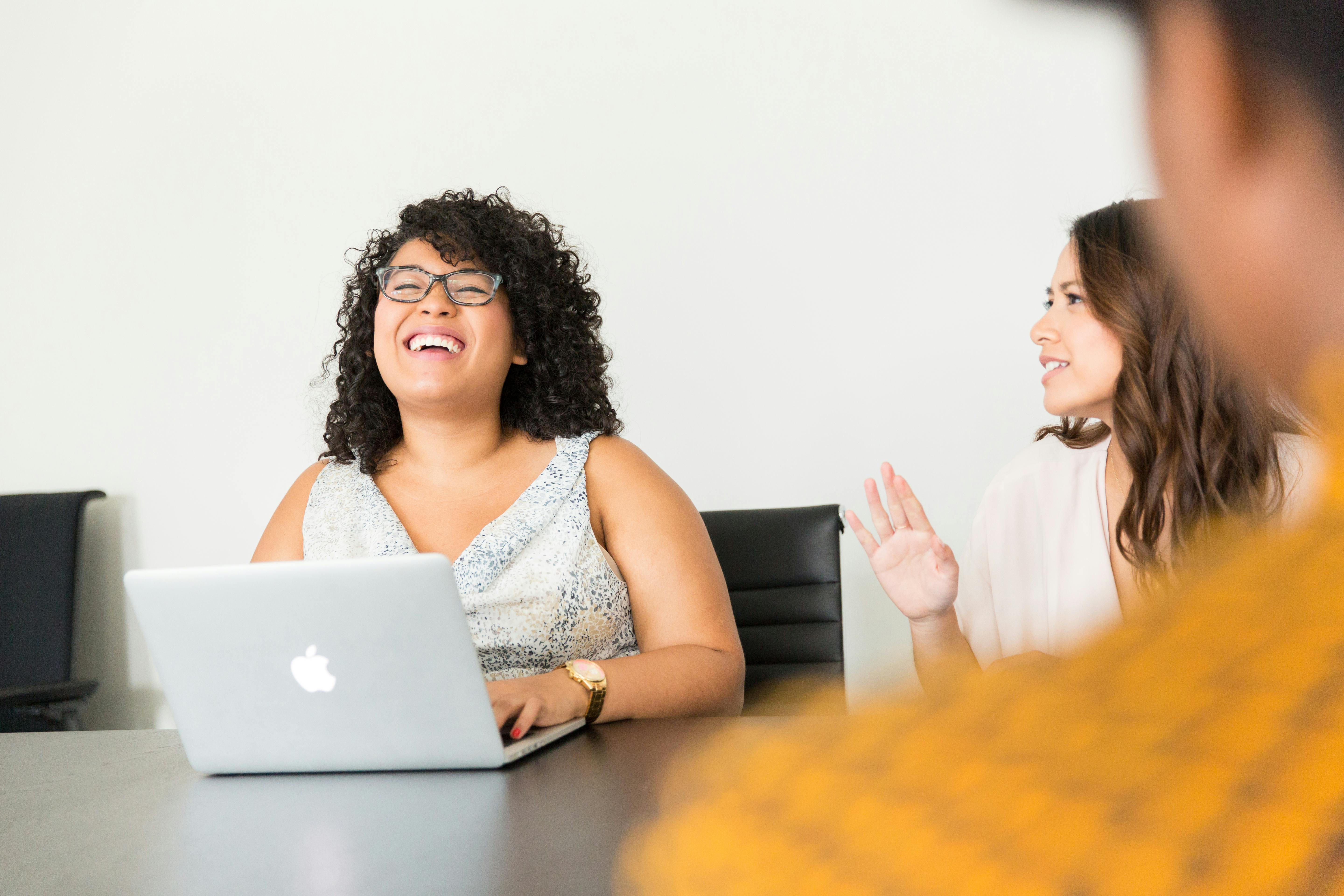 Woman behind her laptop laughing with her colleagues