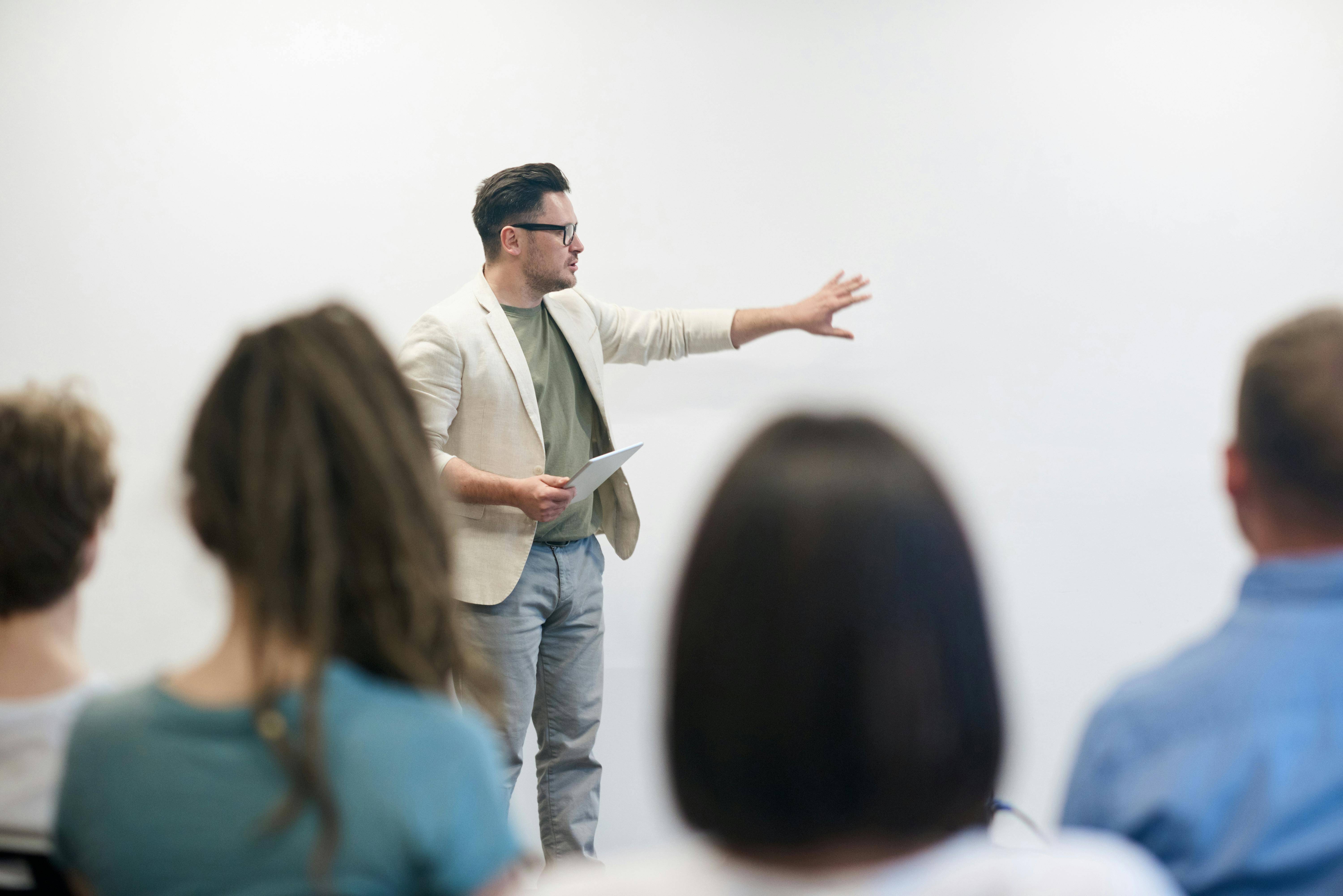 Man talking in front of a whiteboard to a group of university students