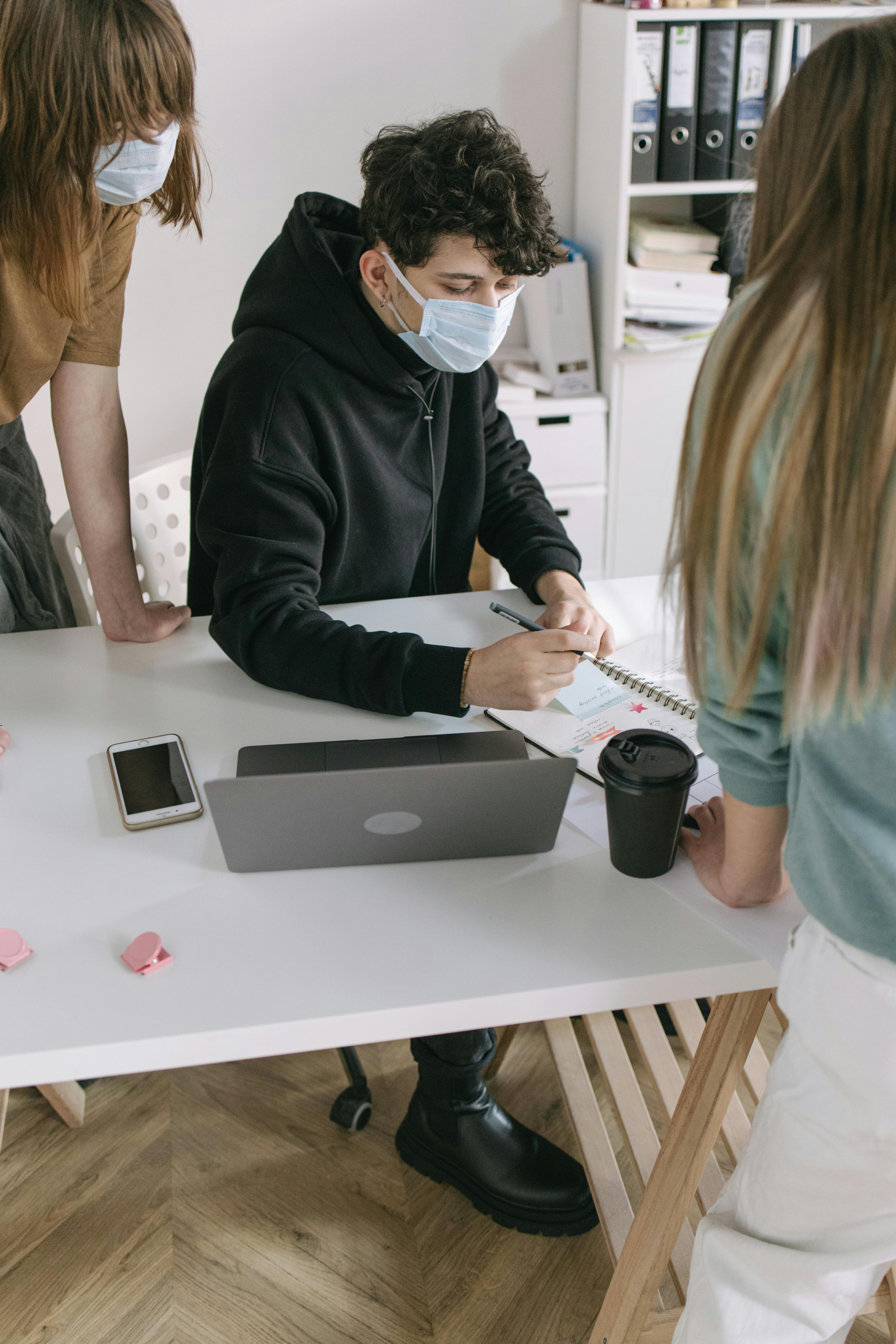 Healthcare graduates sat around a desk wearing face masks