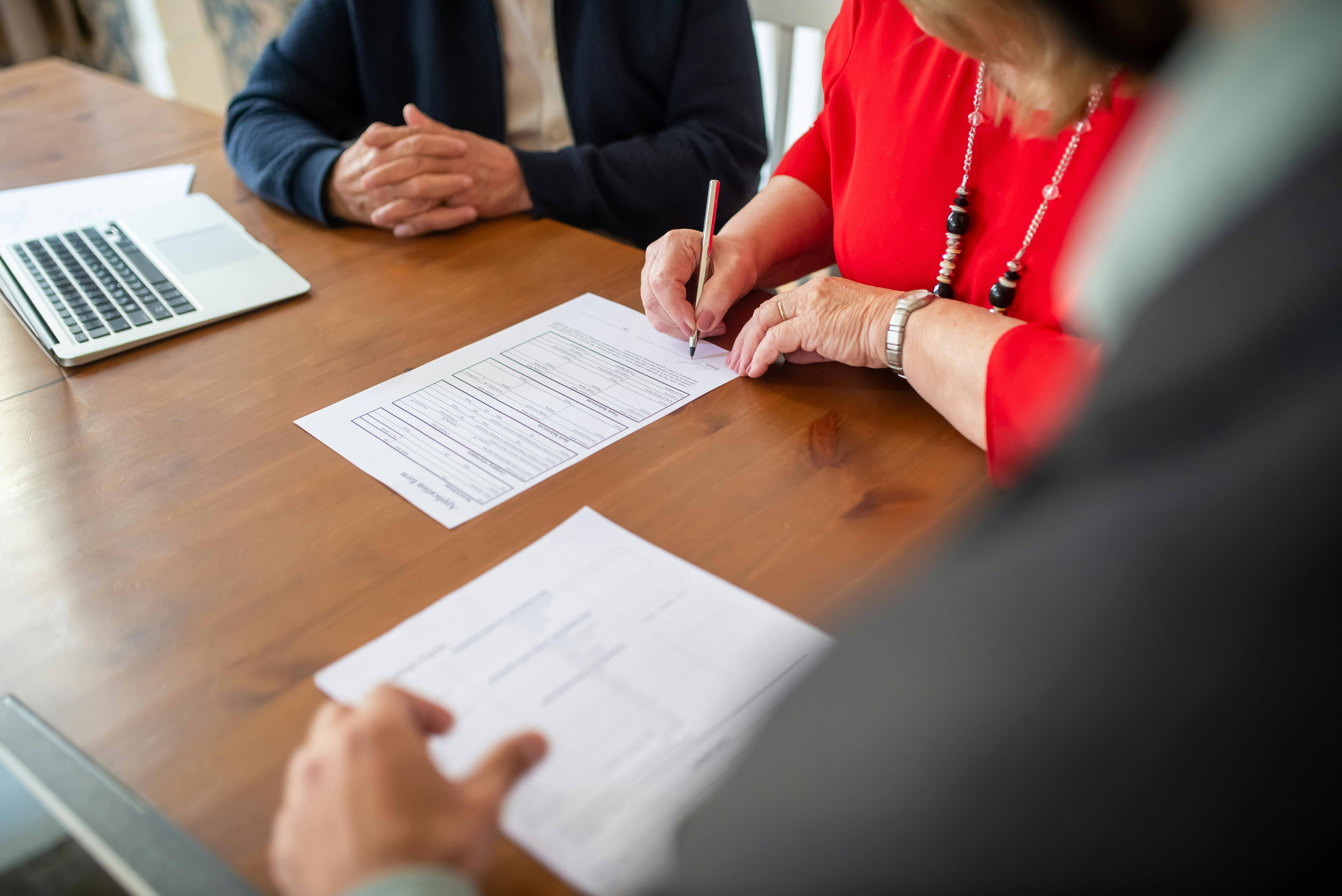 Three people at a desk writing contracts