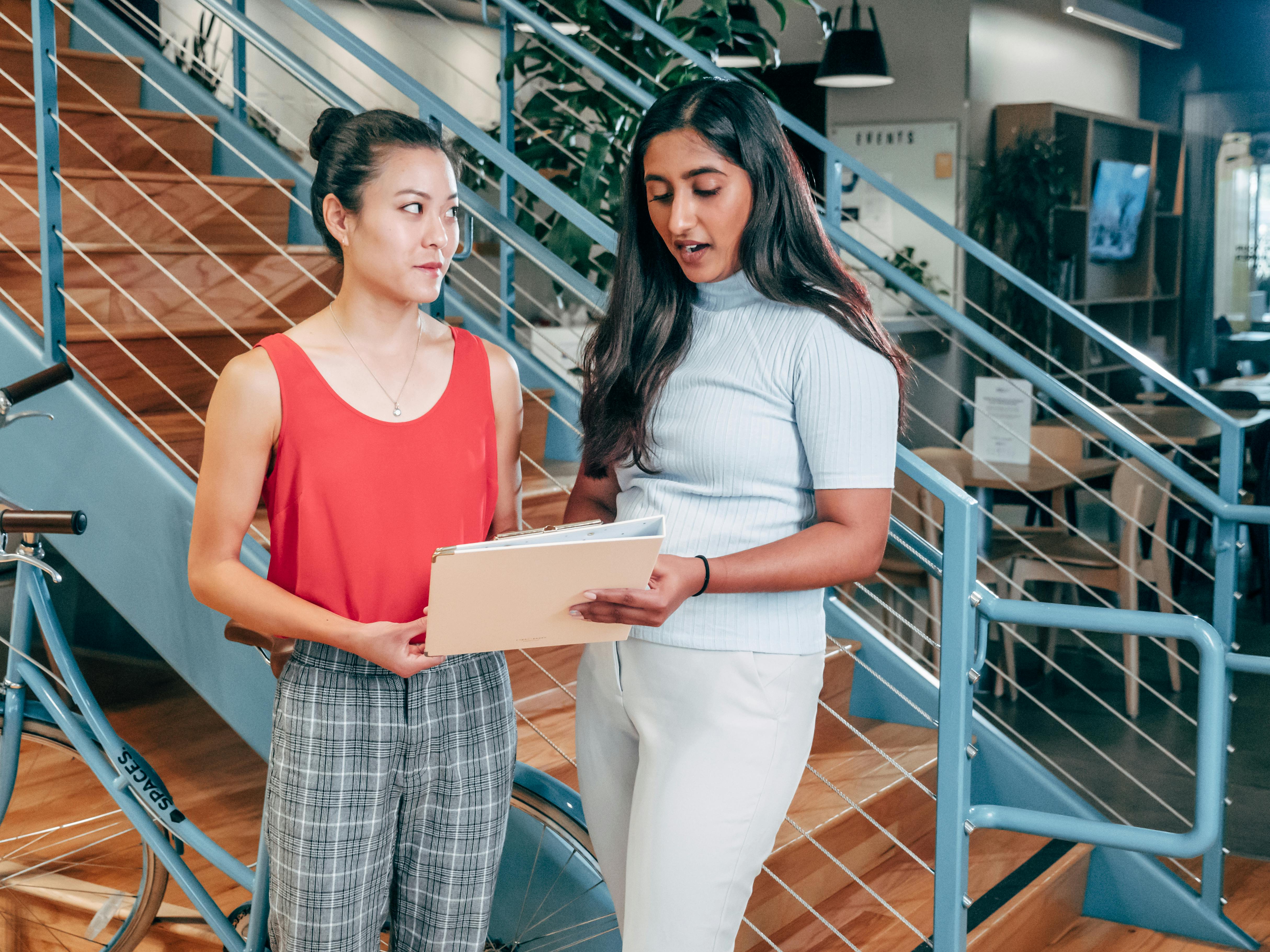 Two women holding papers talking