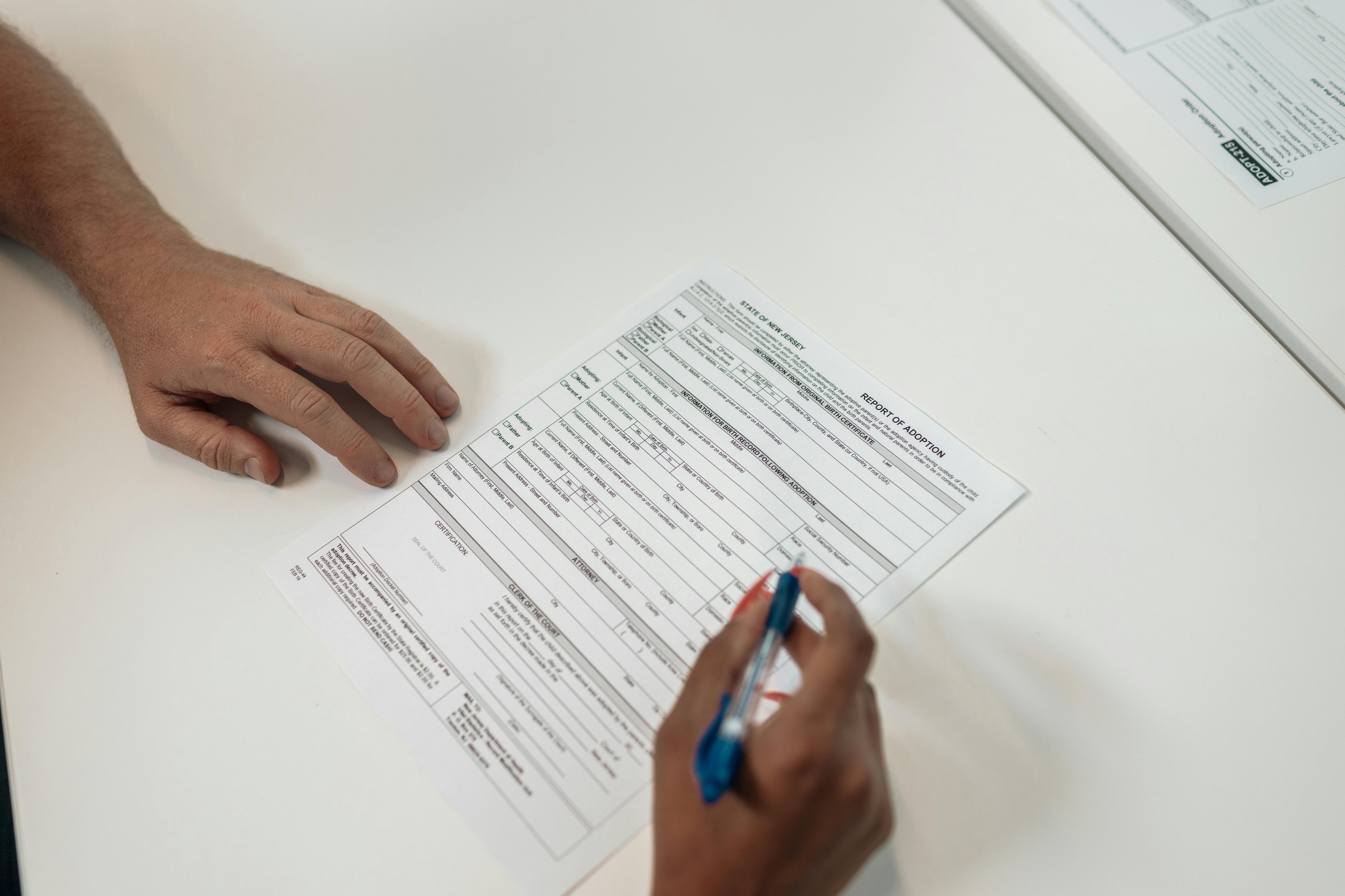 One hand signing a document and the other holding it in place