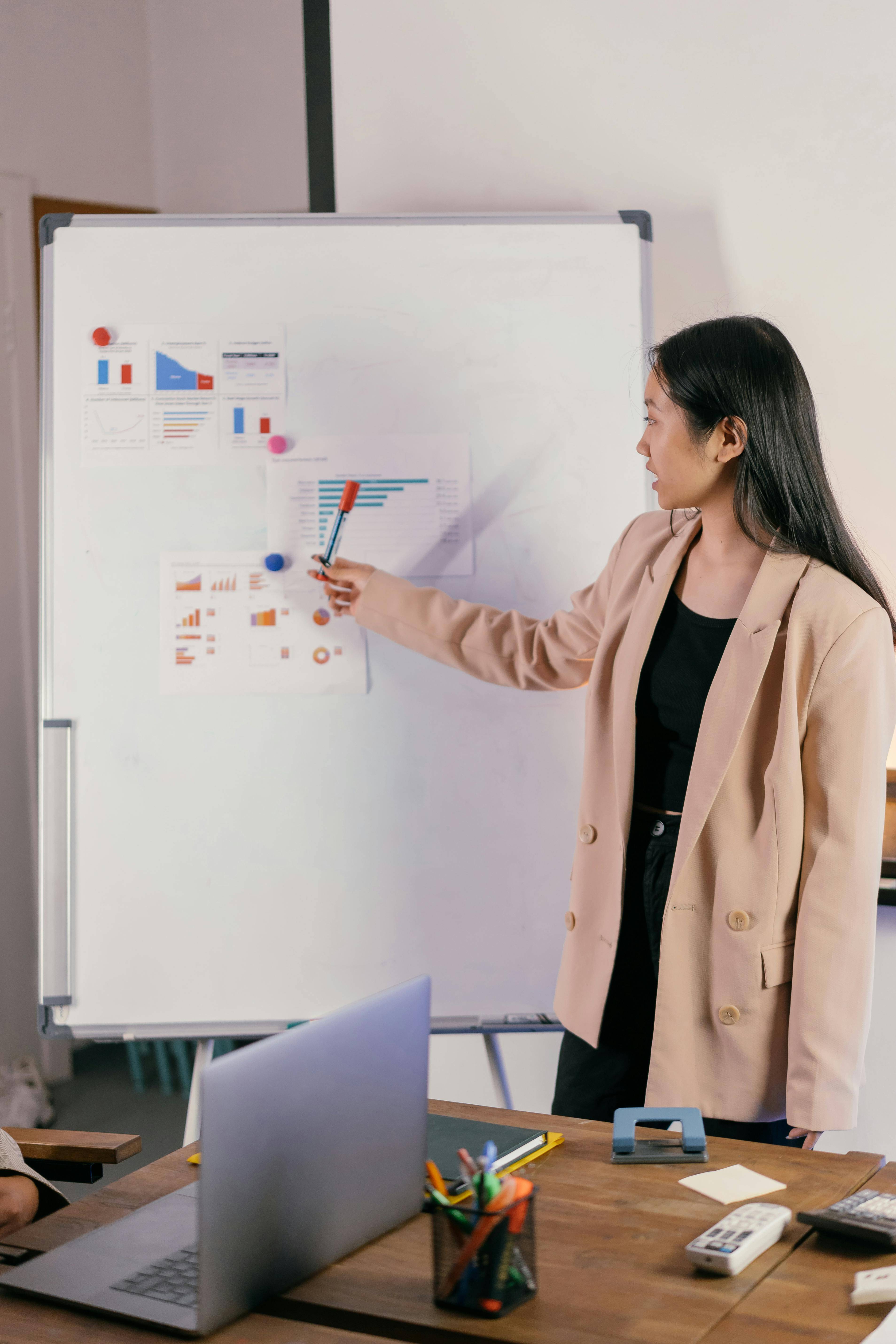 A woman standing in front of a whiteboard covered with reports