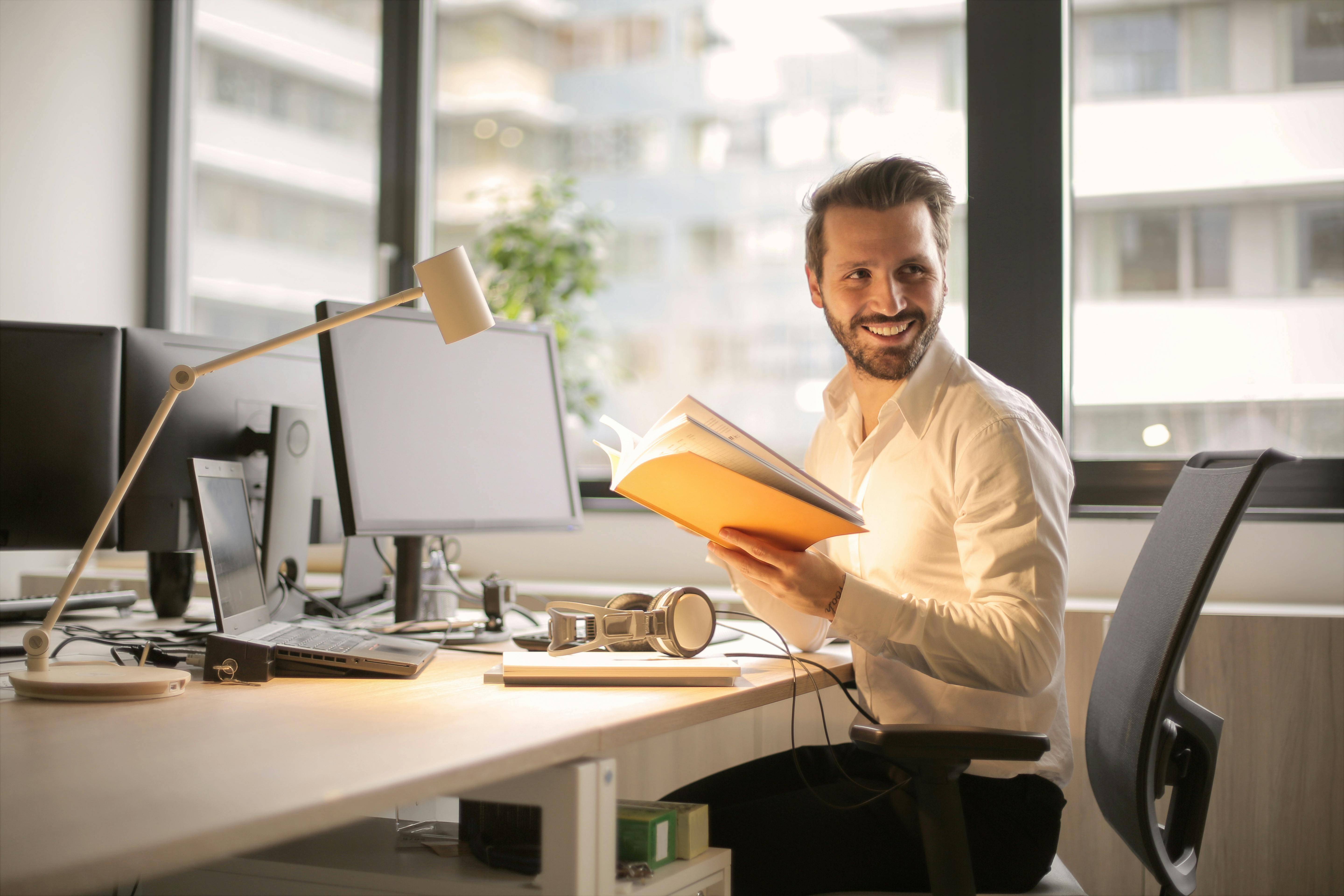 A man sat at his desk with a notebook smiling