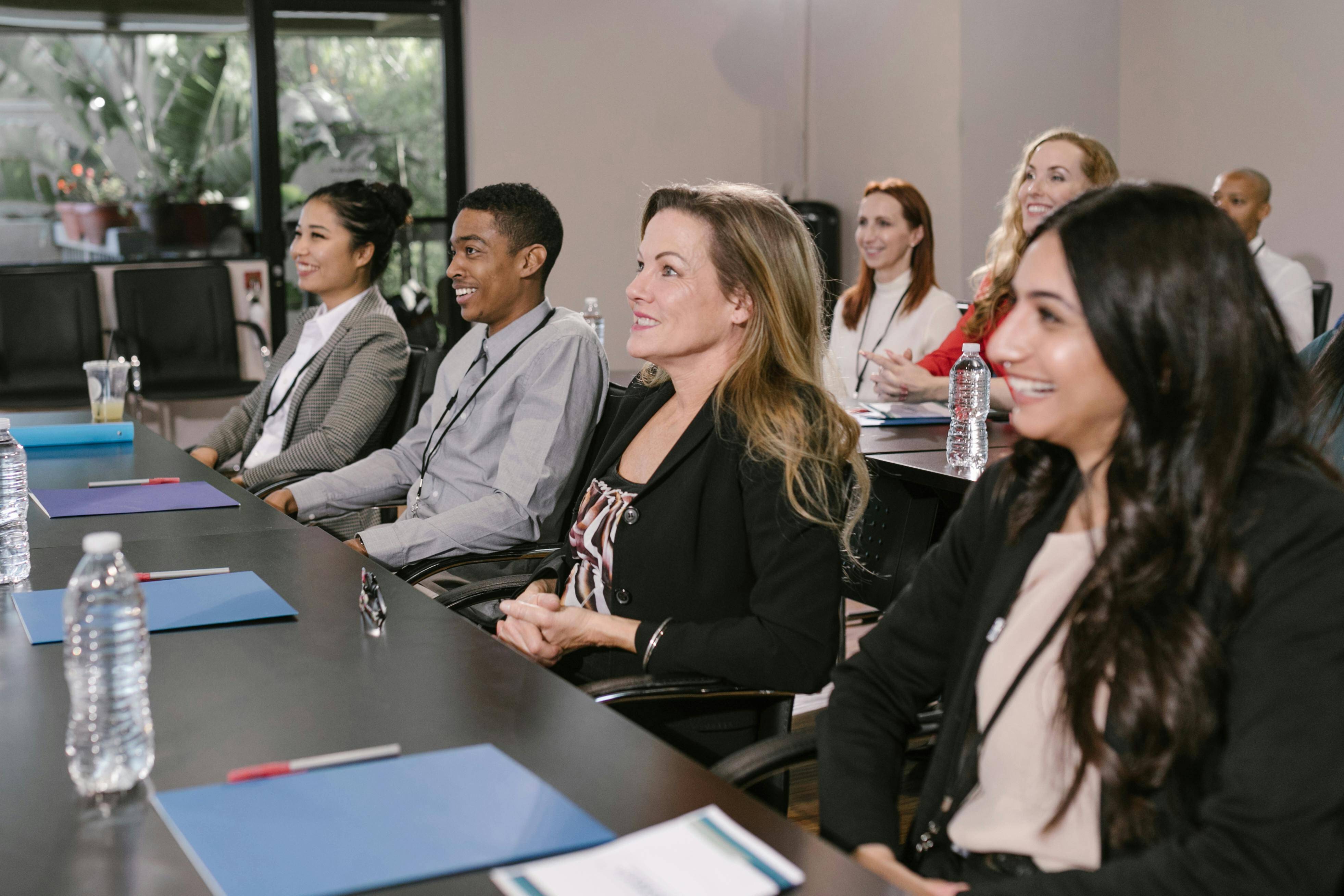 A group of people seated at a desk with others behind them at a corporate event