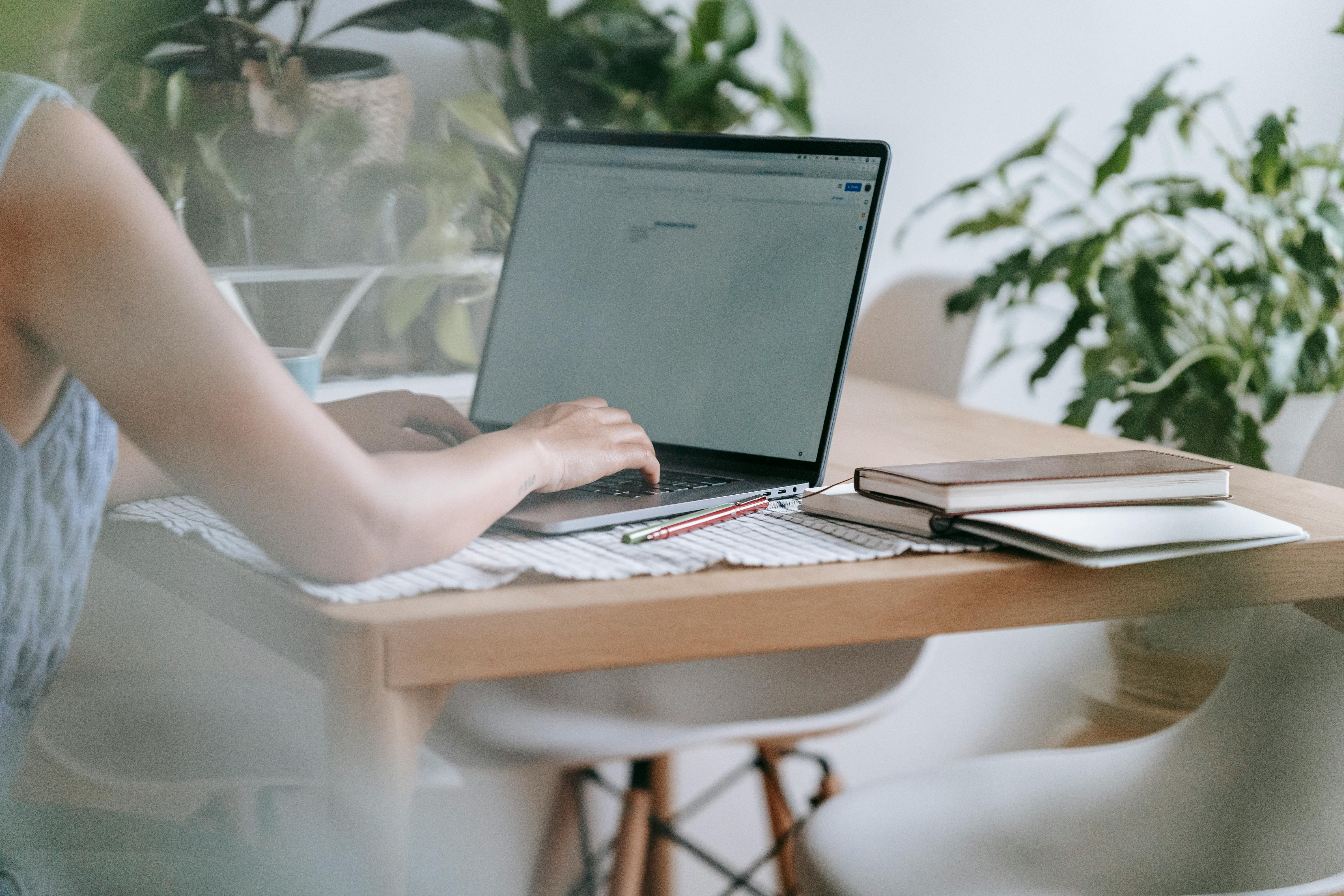 Woman sat at her desk with her laptop and note books, working remotely