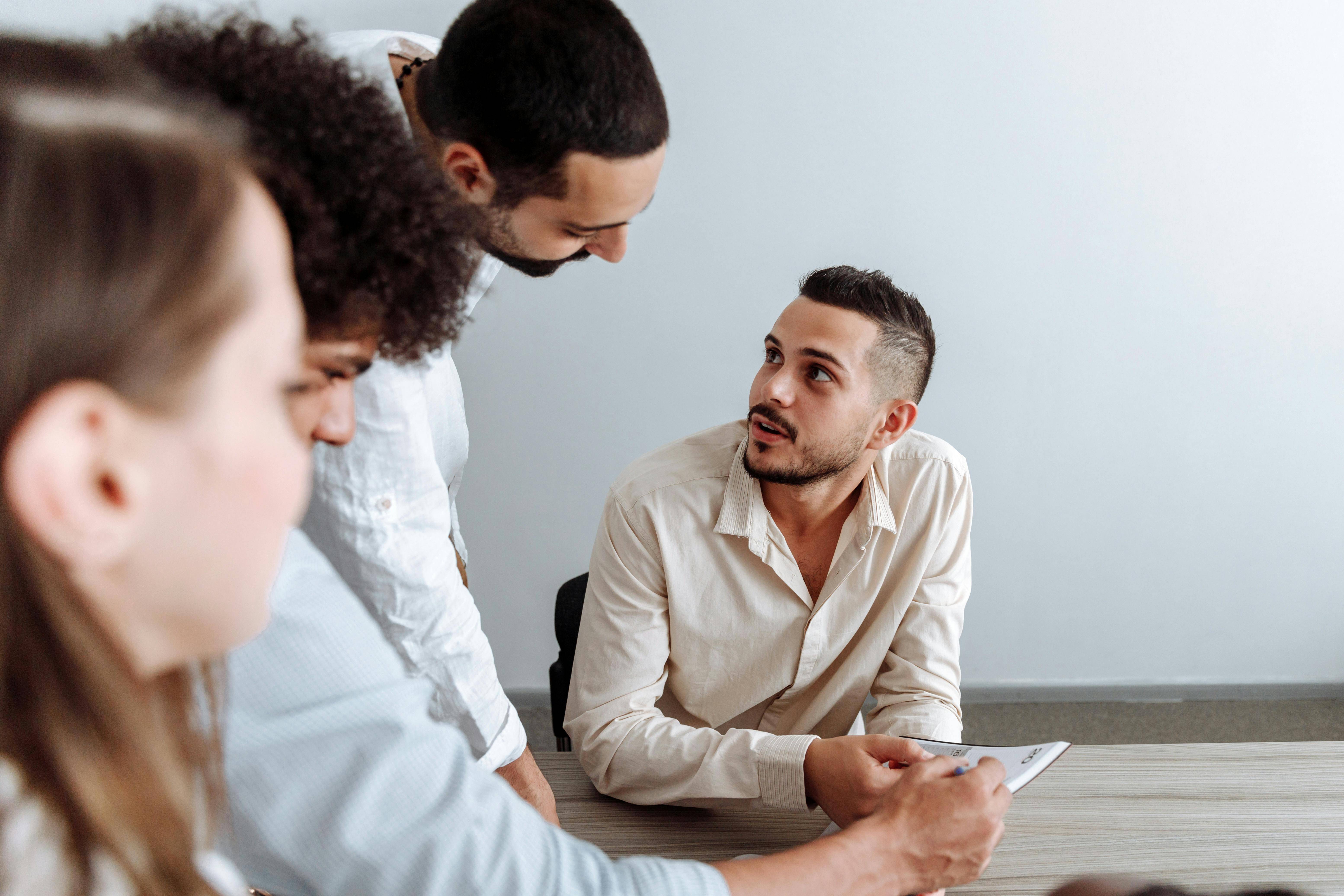 Four people sat at a board table talking